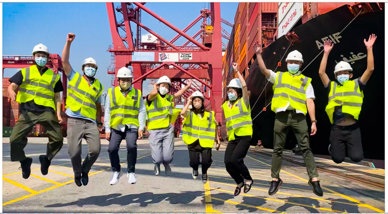 Summer interns jumping in front of a vessel